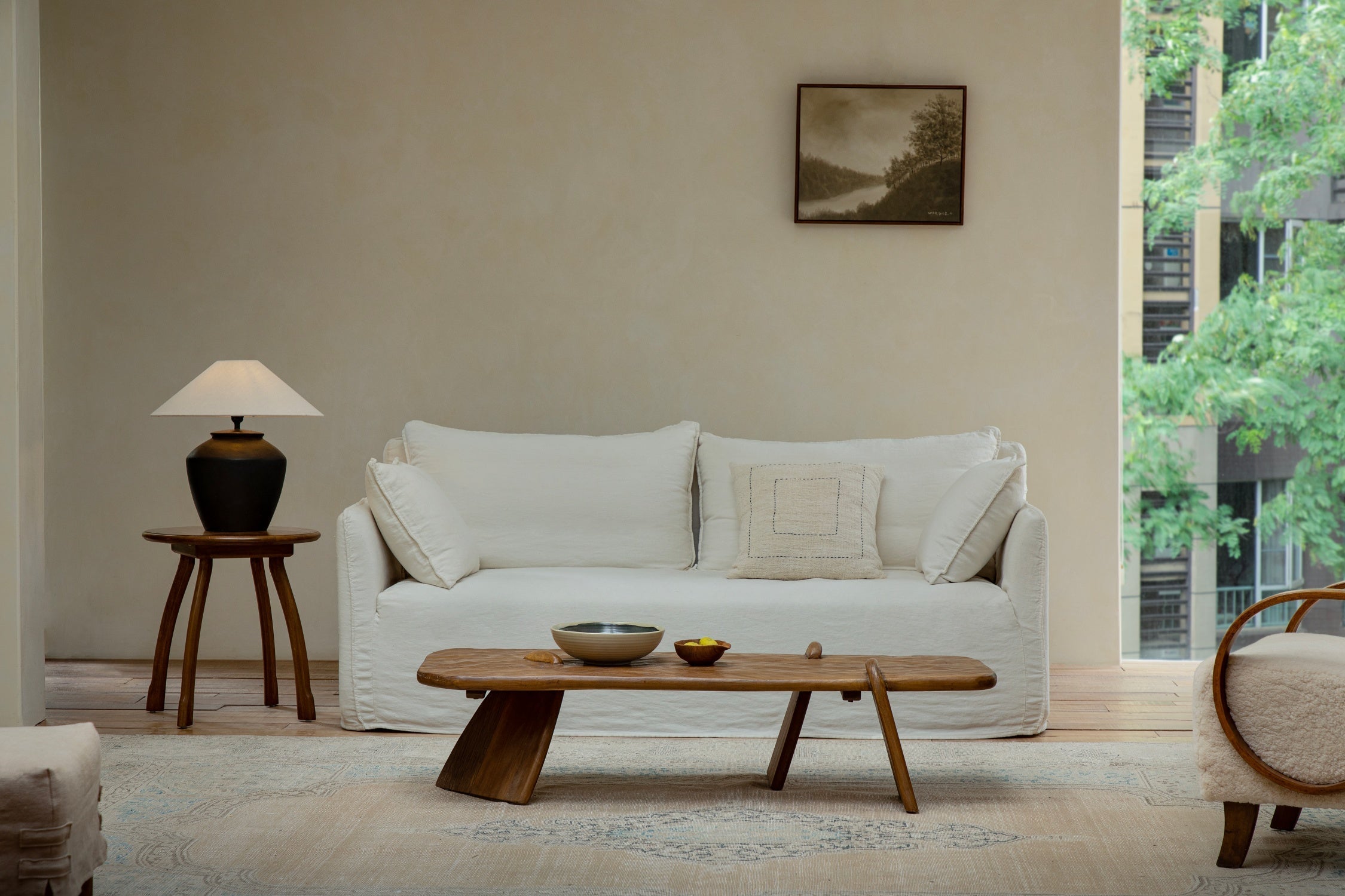 A rustic reclaimed wood coffee table styled with minimal decor and books in a modern, neutral-toned living room.