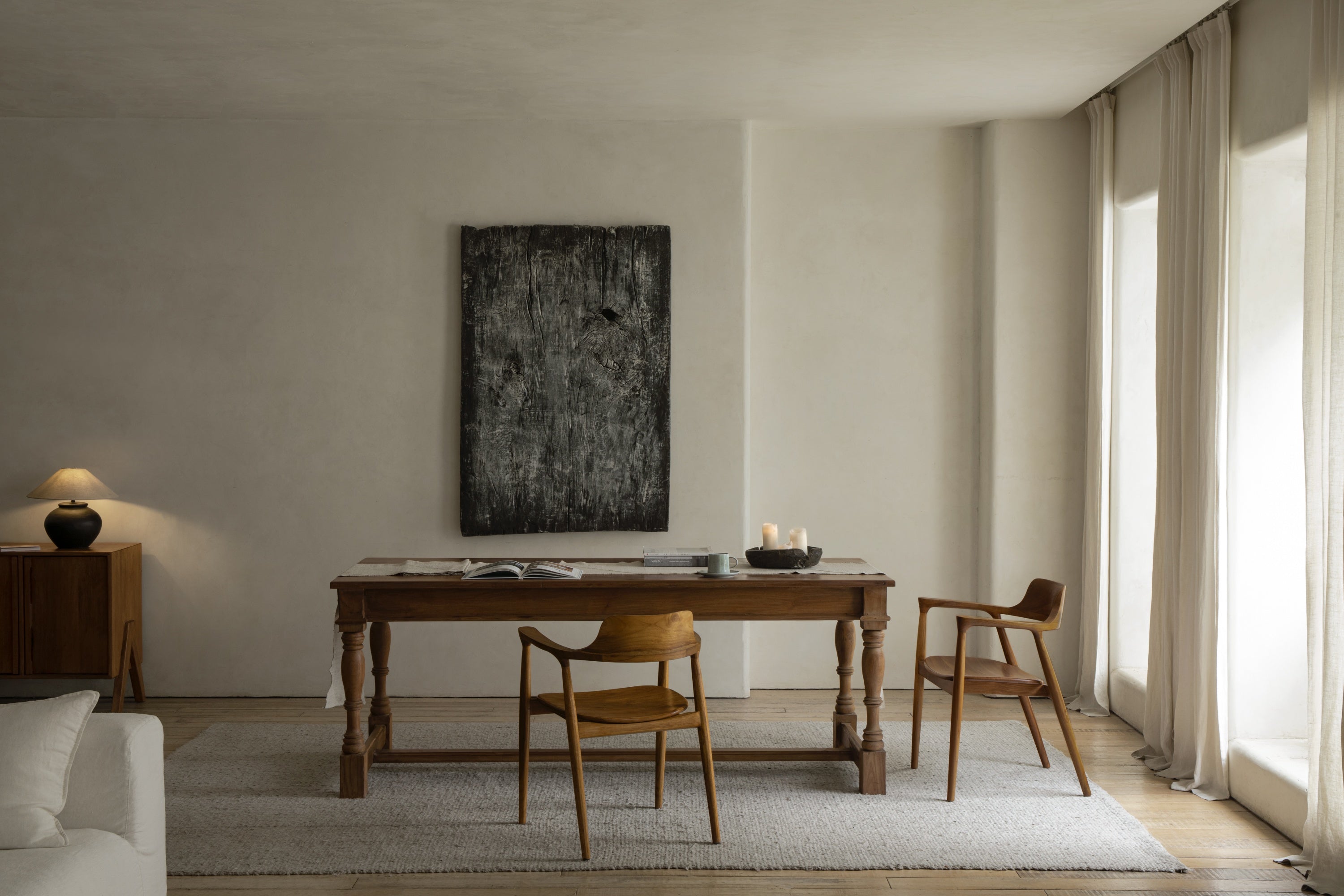 Minimal dining room with wood table, chairs, bench, abstract wall art, rug, and sheer curtains