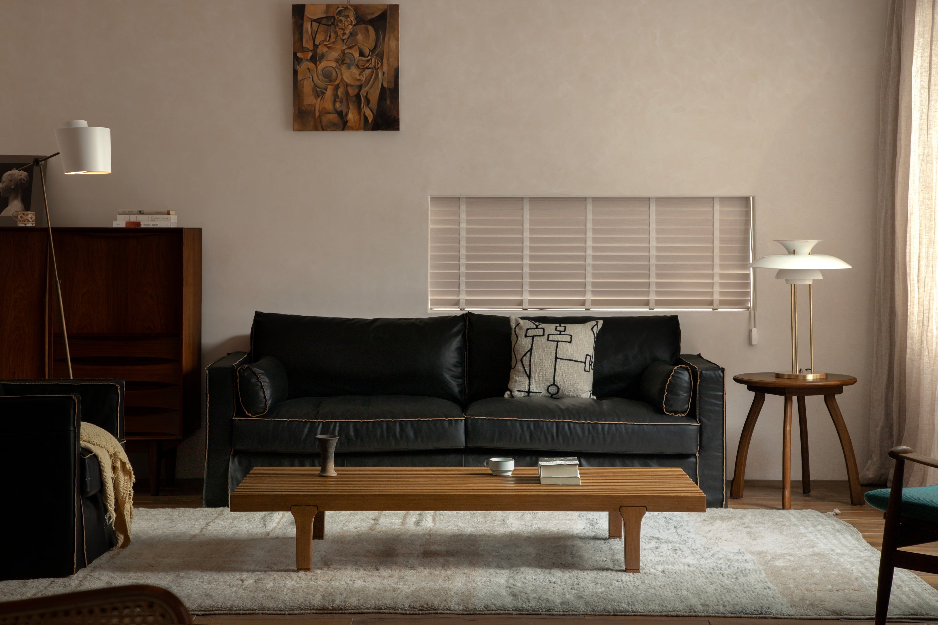 A cozy living room with a black leather sofa, wooden coffee table, and warm lighting.