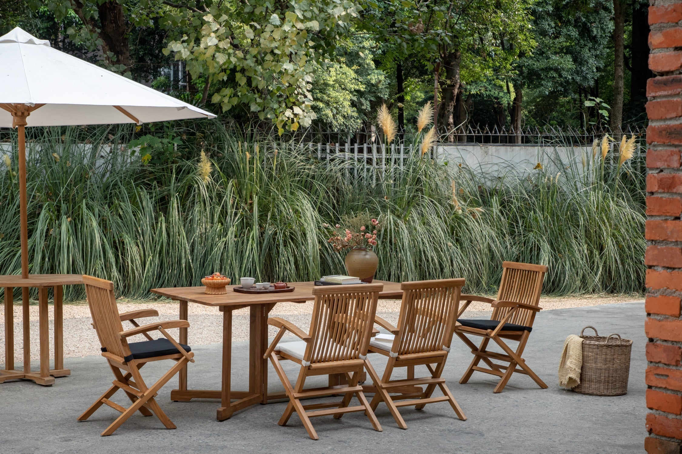 Outdoor wooden dining set with folding chairs and a white umbrella in a garden patio