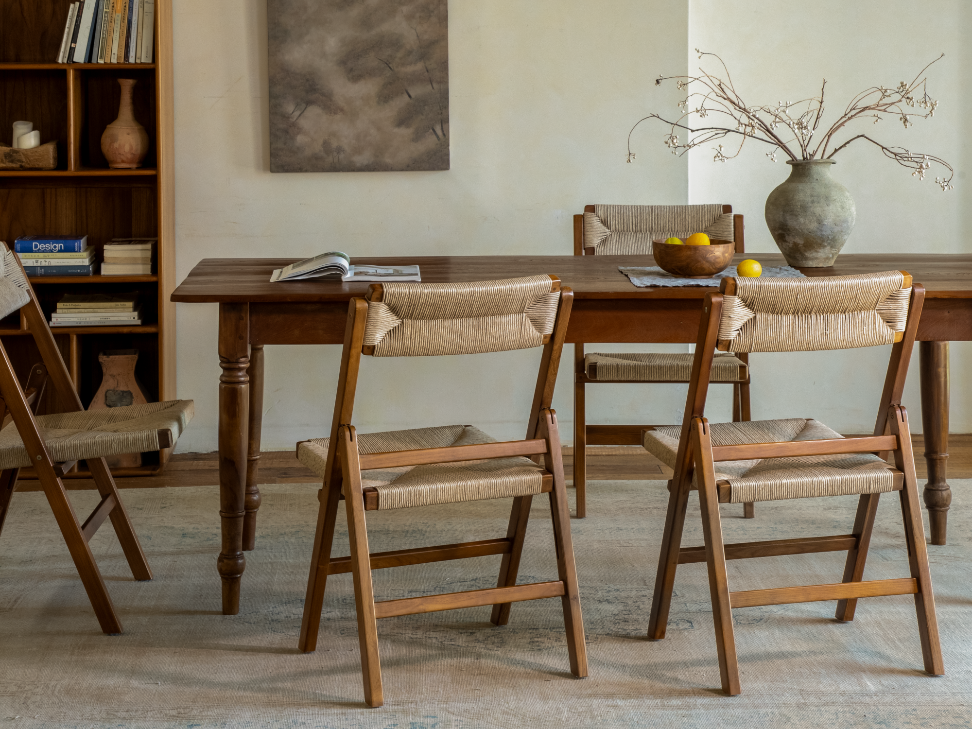 A wooden dining table surrounded by folding chairs in a cozy, minimalist room.