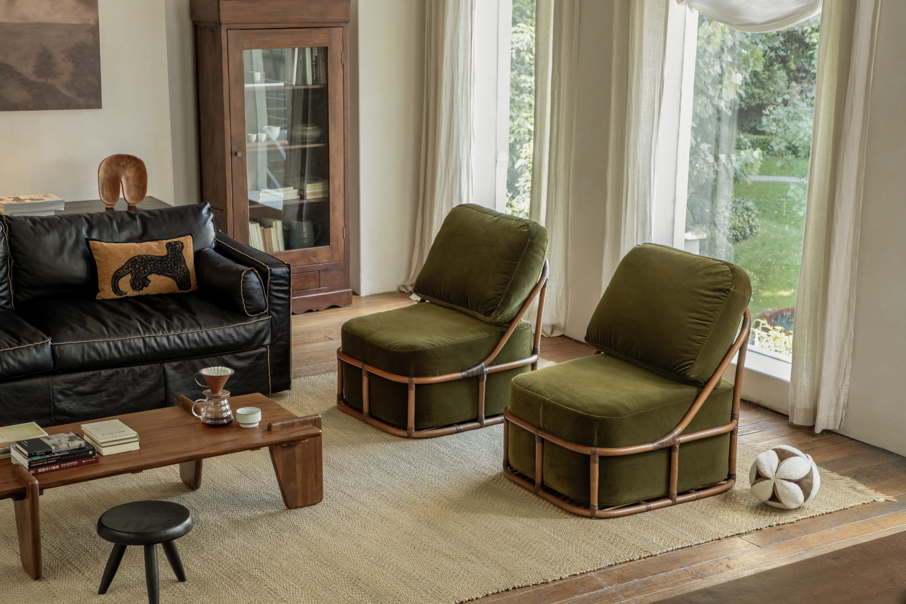 Cozy living room with green lounge chairs, wood coffee table, sofa, rug, and natural window light