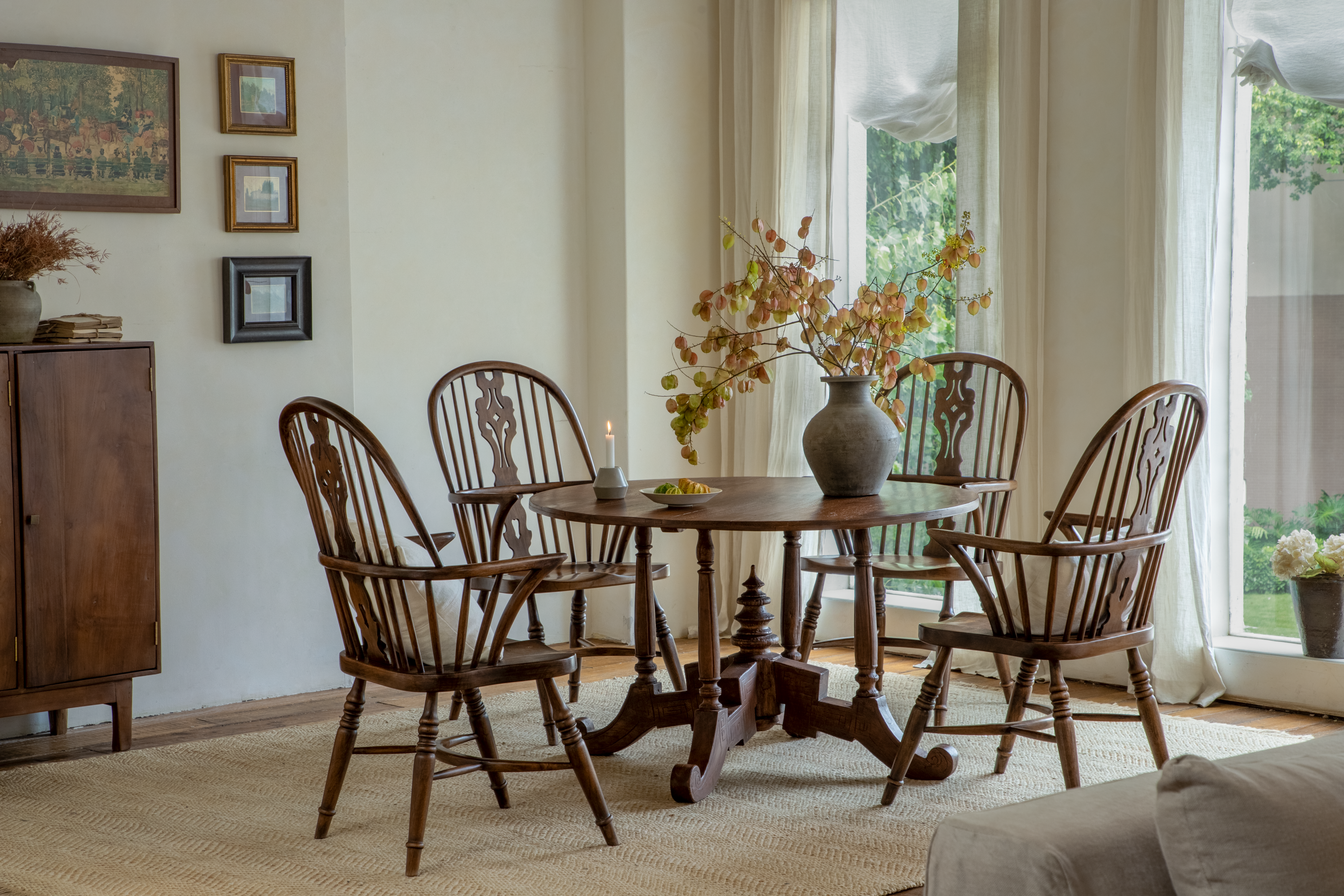 Woven dining chairs surrounding a round wooden table in a bright window-lit dining nook