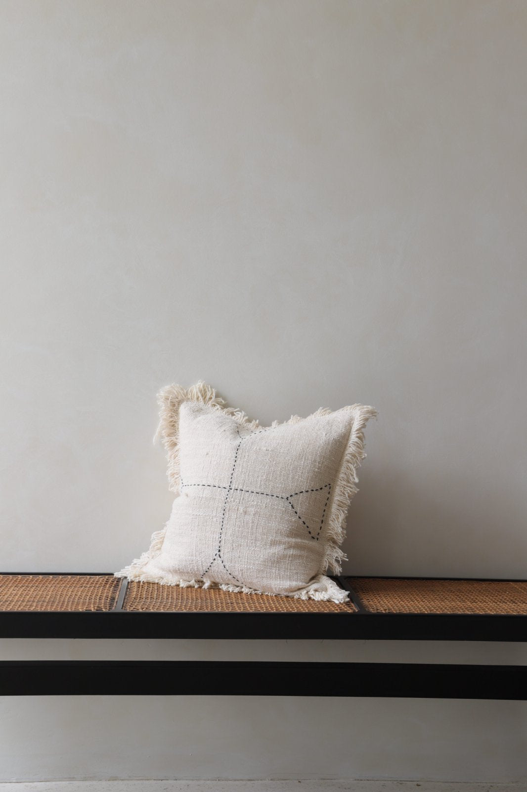 Cotton pillow with geometric design, neutral color, on a bench