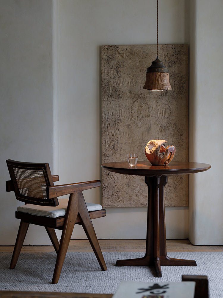 Round wooden X Table with a chair and lamp, showcasing an elegant design.