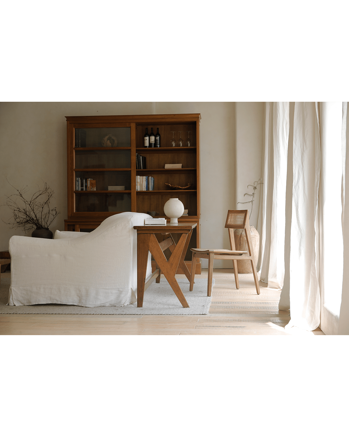 Teak writing desk in home office setting with chair, bookcase, and curtains.
