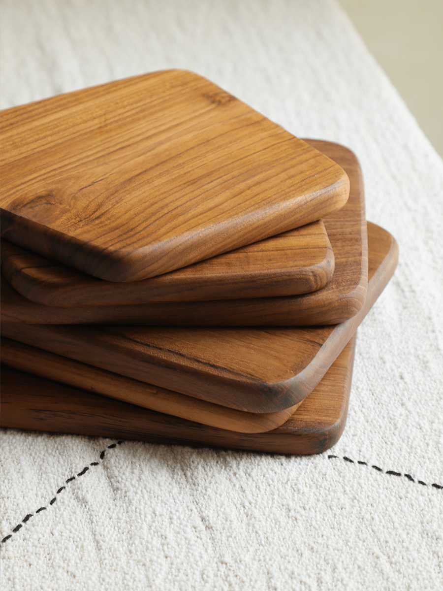 Stack of wooden cutting boards with natural wood grain on white surface