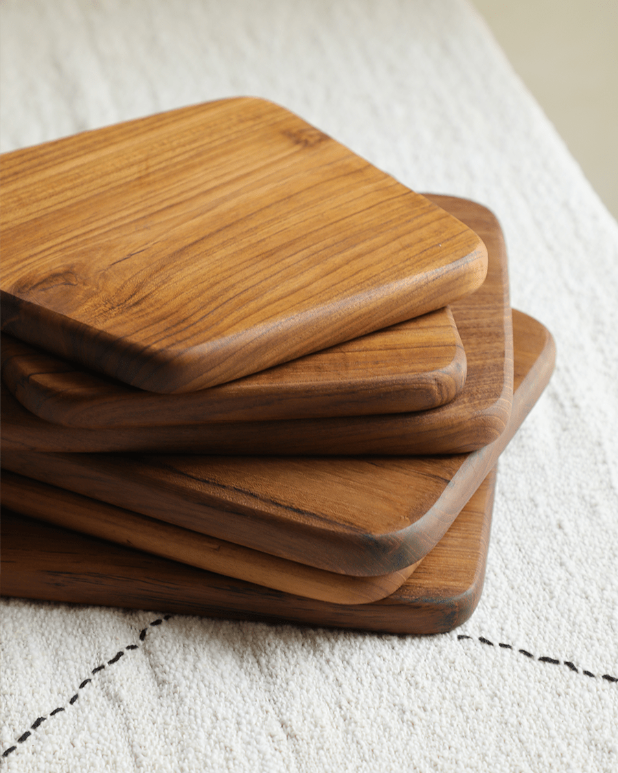 Stack of handcrafted teak cutting boards with rounded edges for kitchen use.