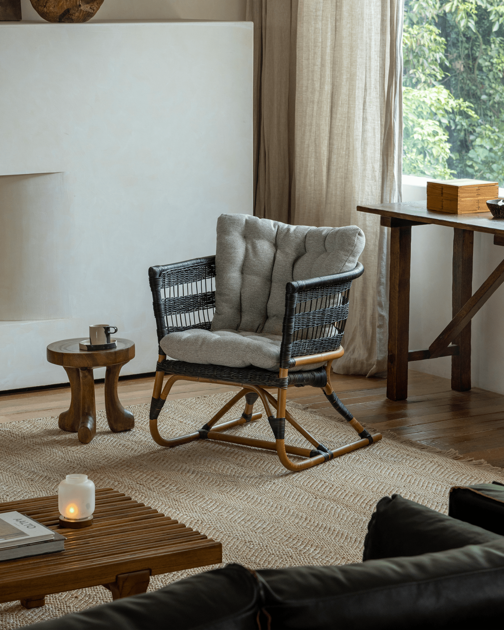 Helian Rattan Chair in cozy interior setting, black rattan frame, gray cushion, and handcrafted design