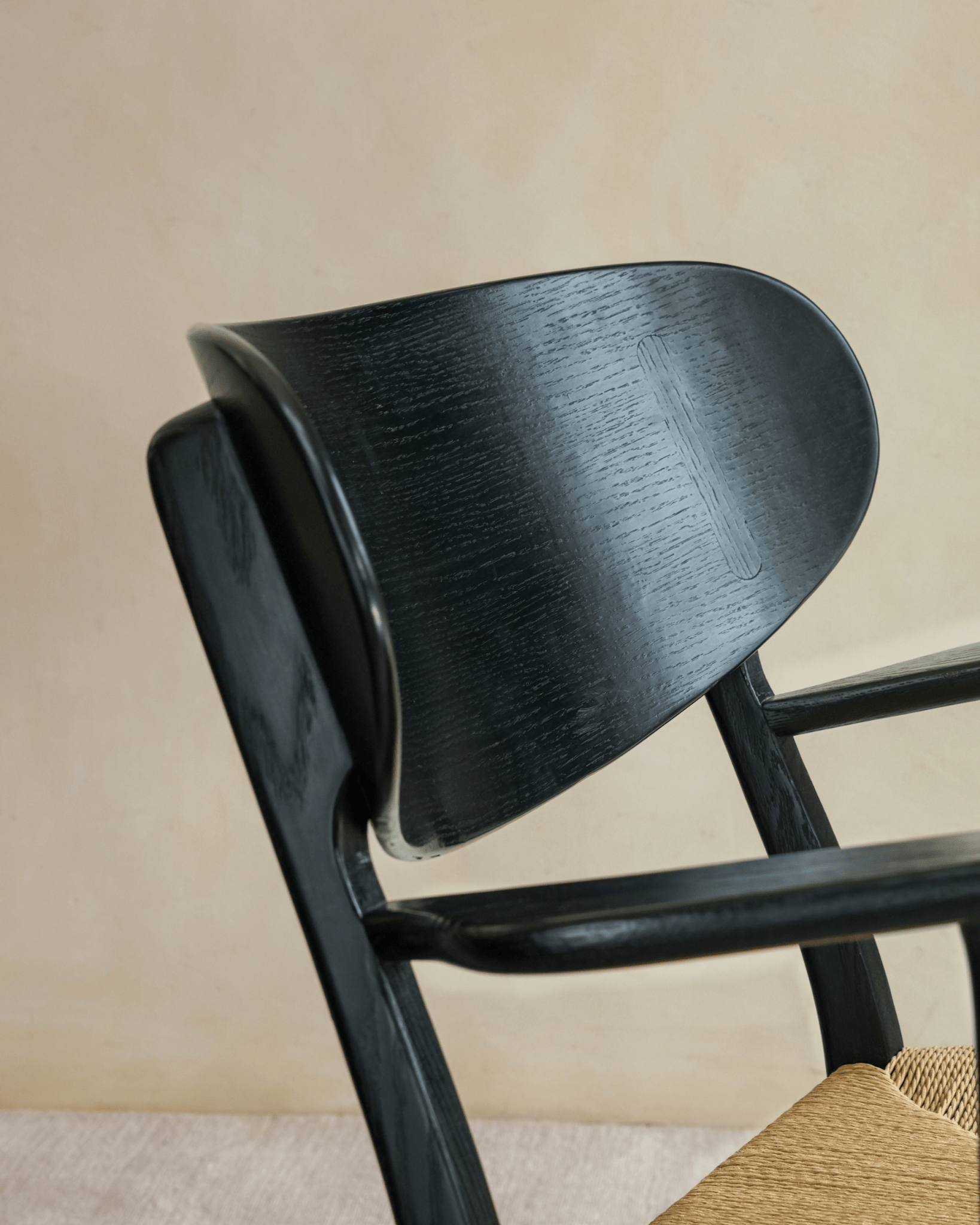 CH22 Lounge Chair detail: black oak frame, ergonomic design, and woven paper cord seat. Modern Scandinavian design icon.