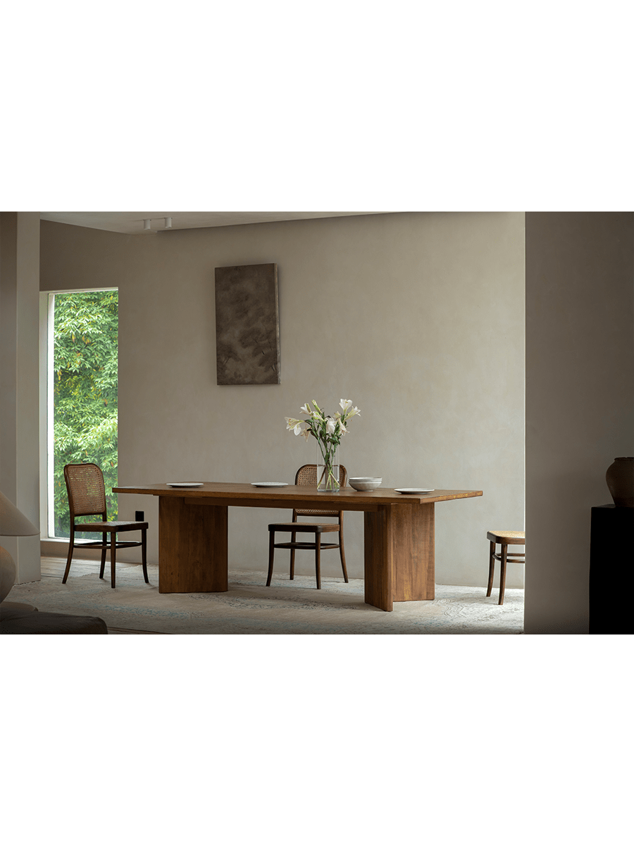 Zephyr Dining Table in a bright, minimalist dining room setting with matching woven chairs and decor.