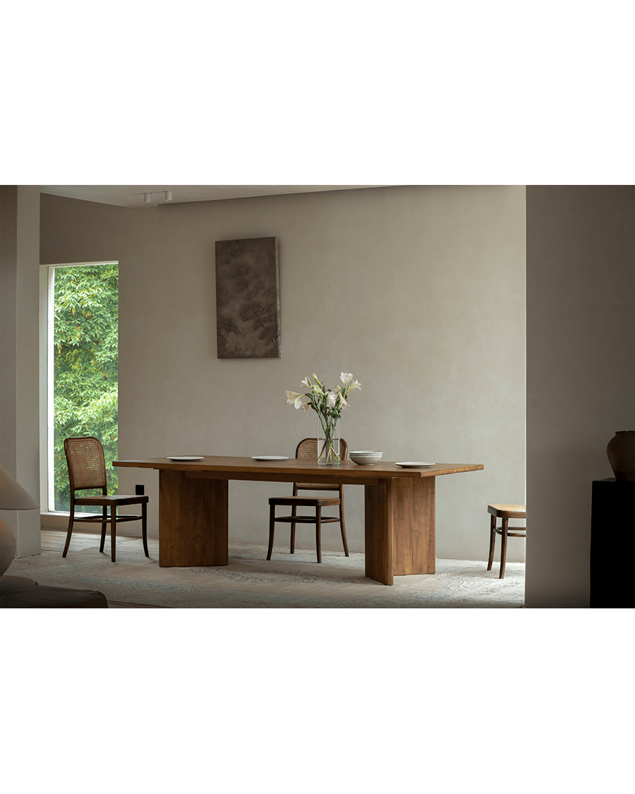 Zephyr Dining Table in a bright, minimalist dining room setting with matching woven chairs and decor.