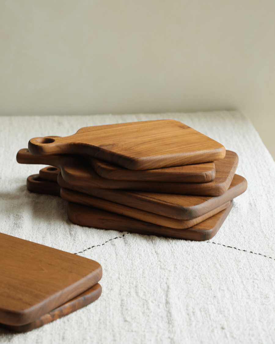 Stack of handcrafted teak wood cutting boards with handles