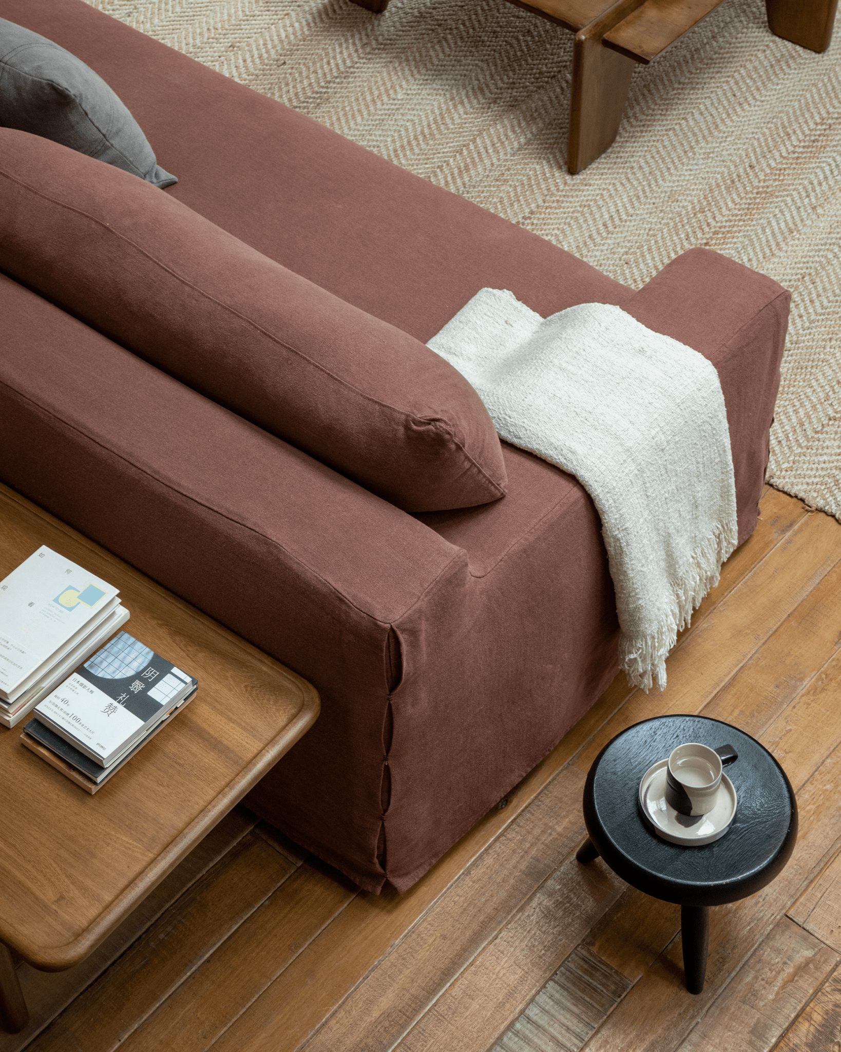 Guni terracotta linen sofa with decorative pillows, books, and a coffee table, showcasing the sofa's cozy design.