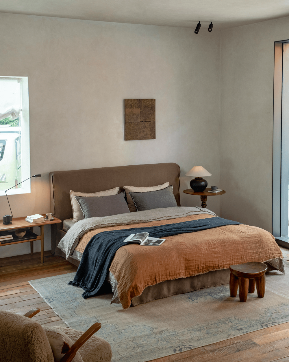 Freya Linen Bed in a modern bedroom setting, terracotta linen with dark blue blanket and wooden side table