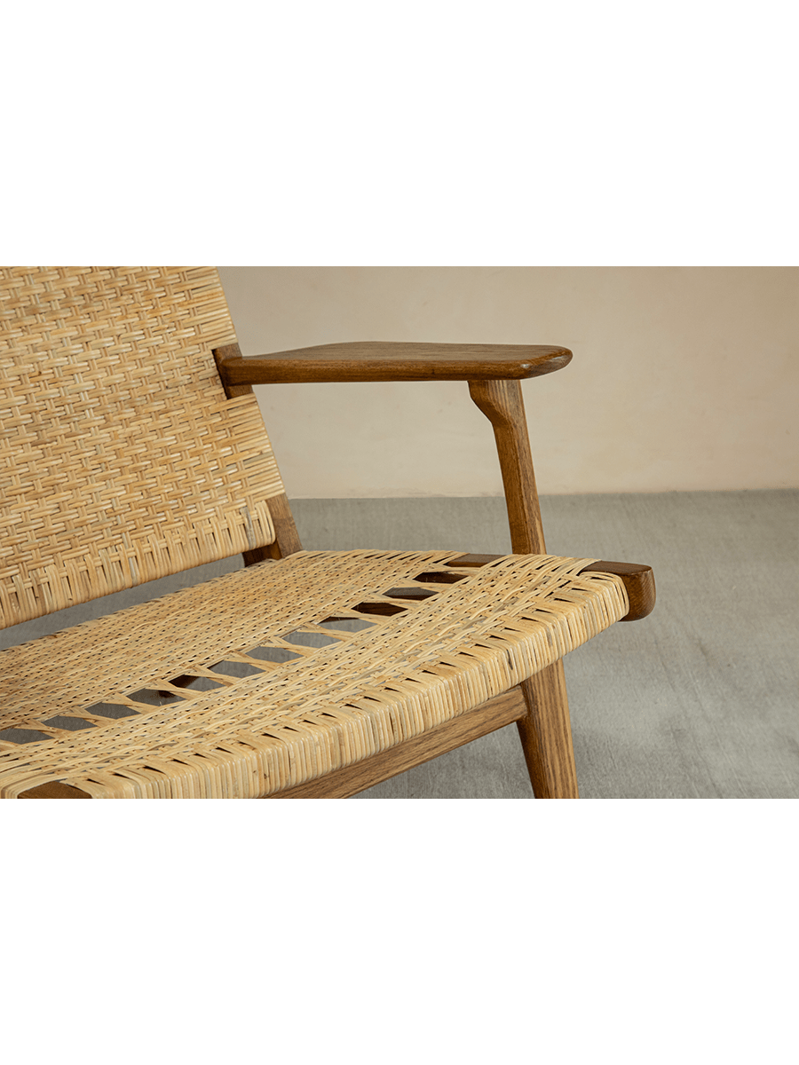 Horn Lounge Chair detail: natural rattan seat and oak frame, ergonomic design. Handcrafted for interior decor.