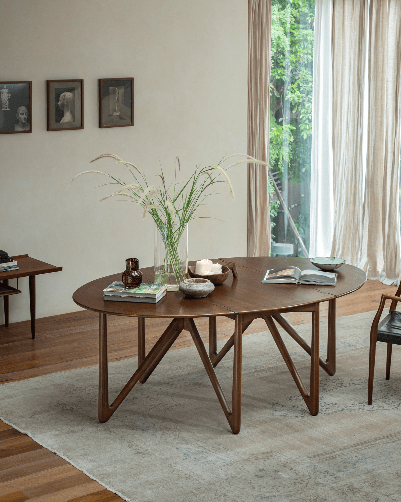 Niels Folding Table in teak wood, extended, showcasing V-shaped legs in a well-lit room setting.