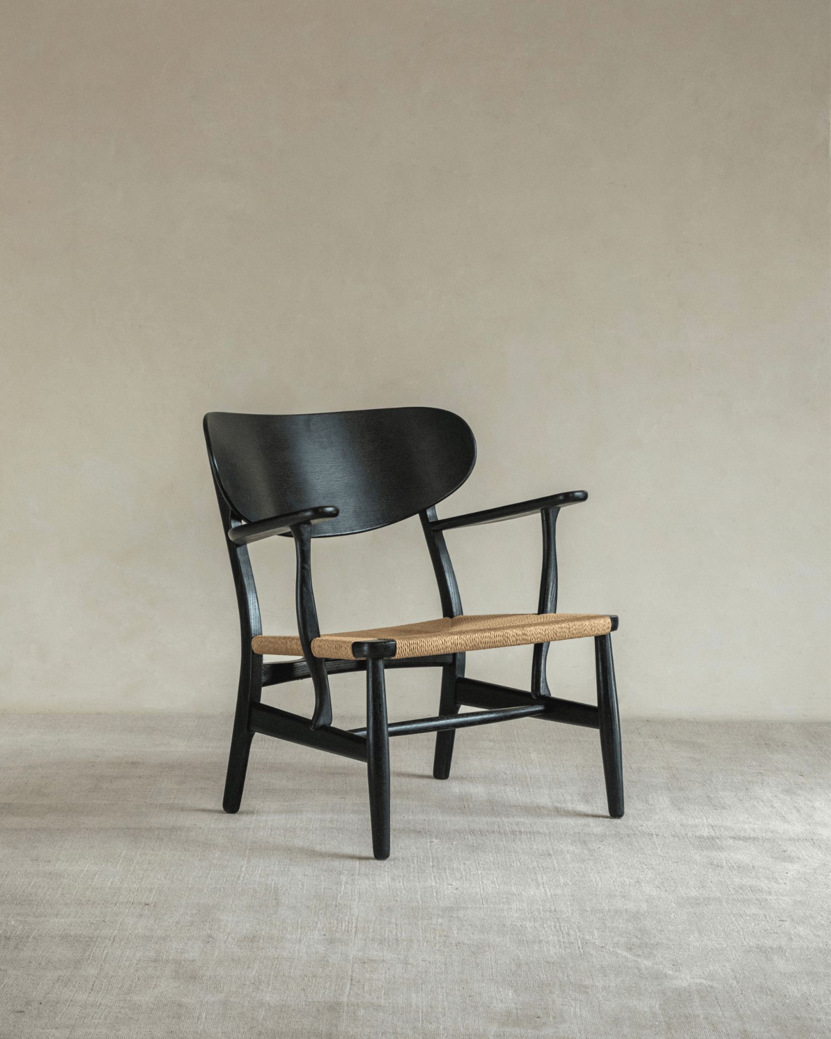 CH22 Lounge Chair with black frame and woven paper cord seat. Scandinavian design icon.