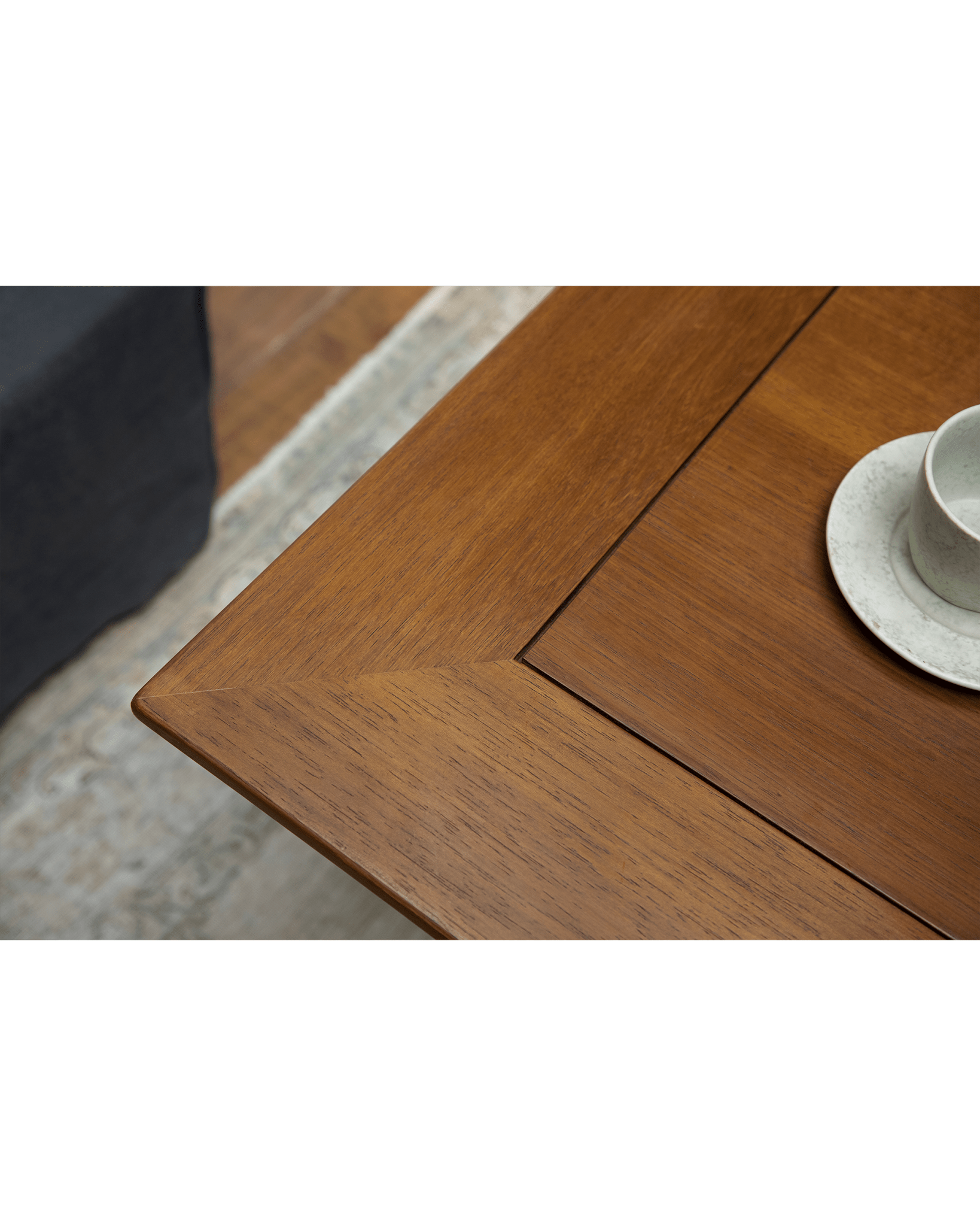 Titan Teak Dining Table detail with teak wood grain and cup. Stylish design for dining or leisure.