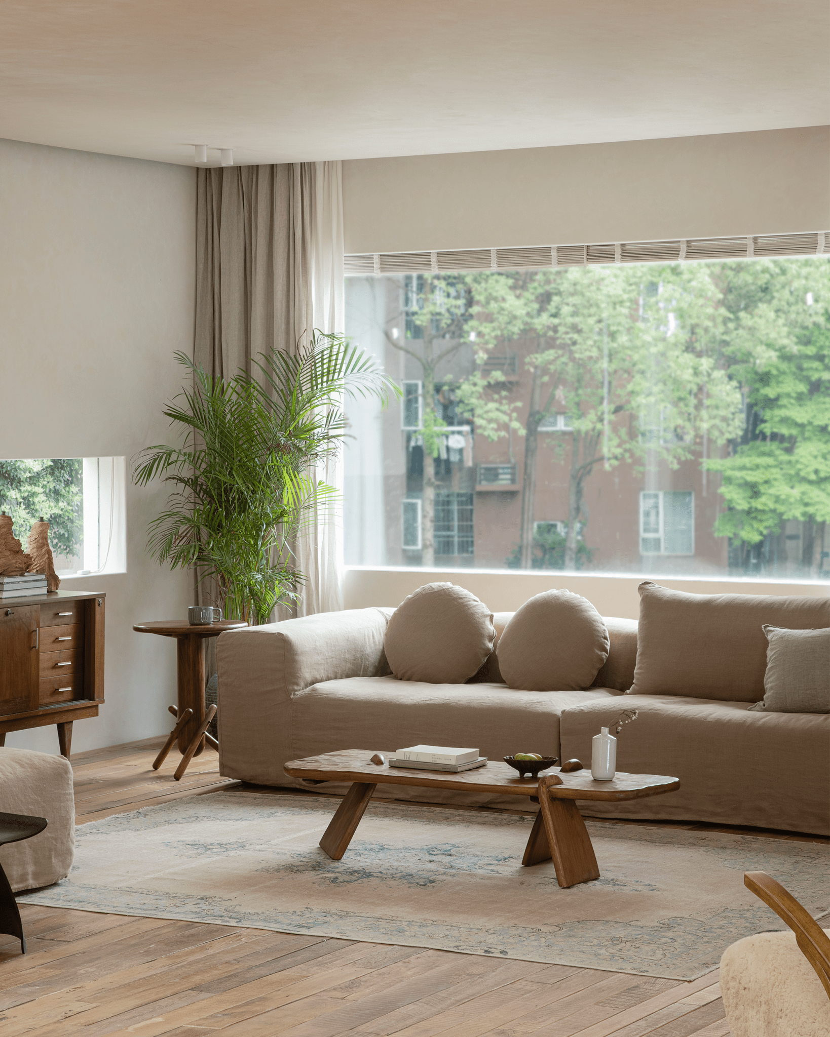 Doma sectional sofa in linen with wide armrests in a bright living room. Features a relaxed aesthetic with city views.