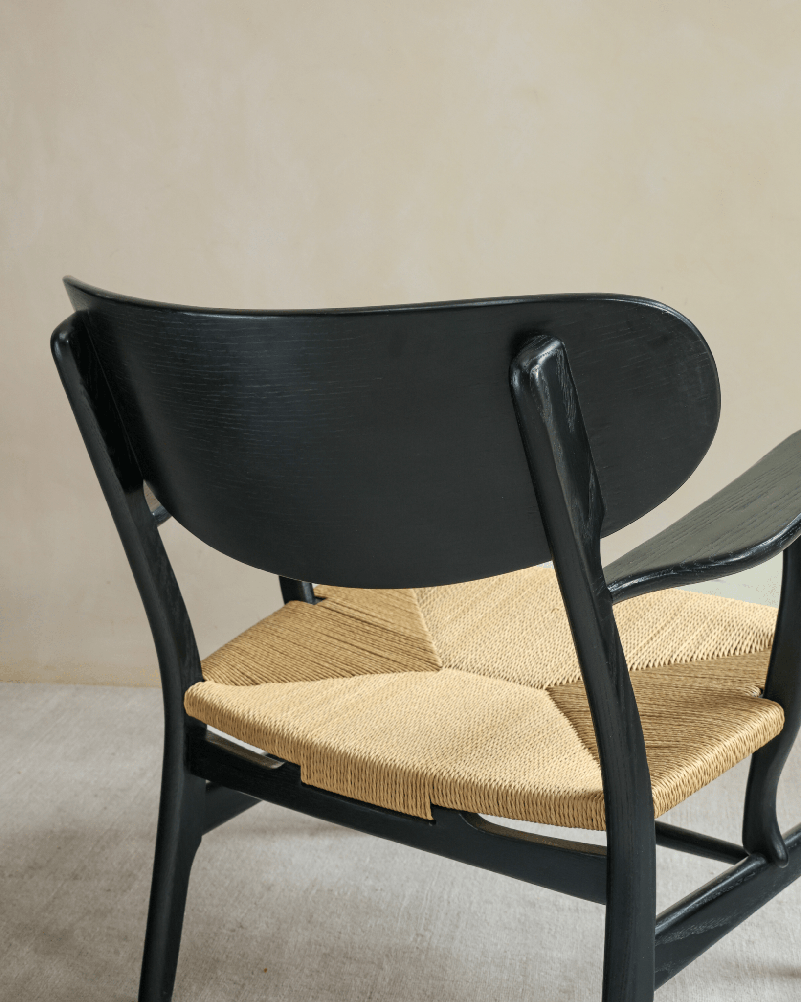 CH22 Lounge Chair detail: Black frame, woven paper cord seat, ergonomic design, Scandinavian aesthetic