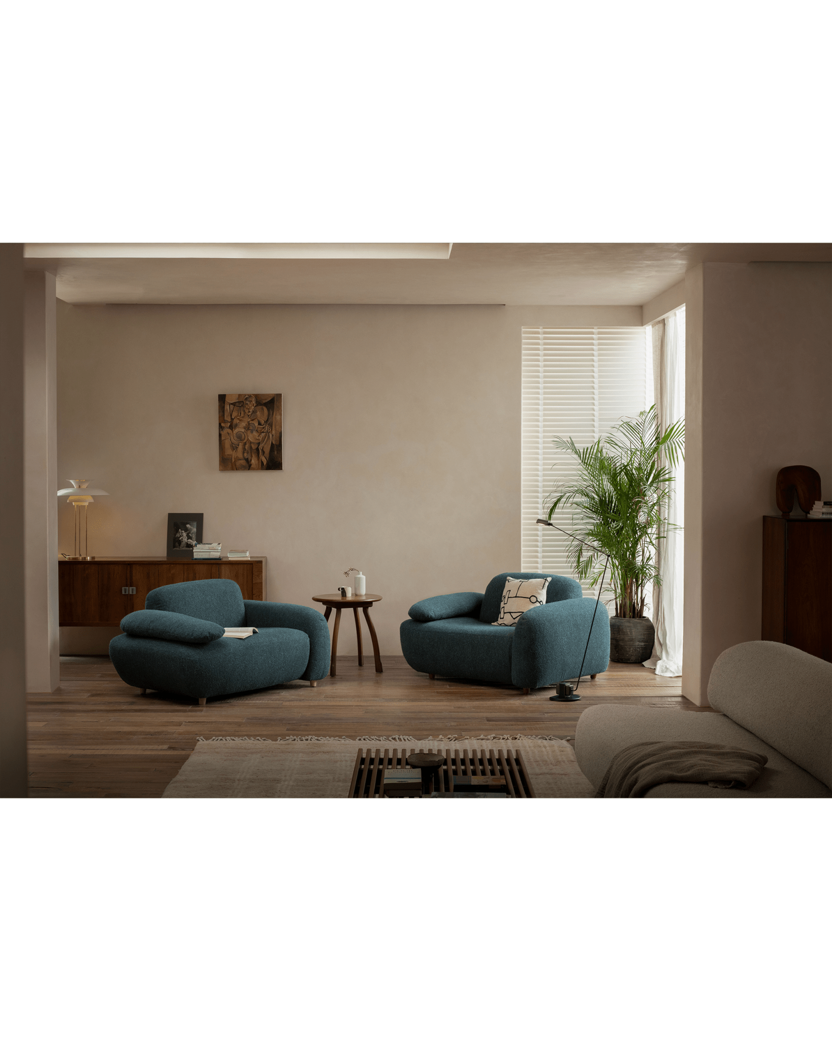 Cozy living room with teal armchairs, Phoebe wood side table, and Ele round side table