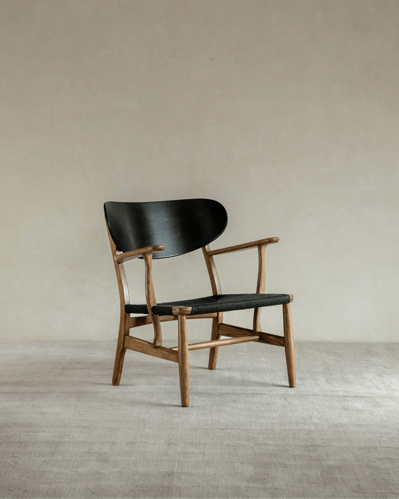 CH22 Lounge Chair with black backrest and woven paper cord seat, oak frame. Danish design for modern interiors
