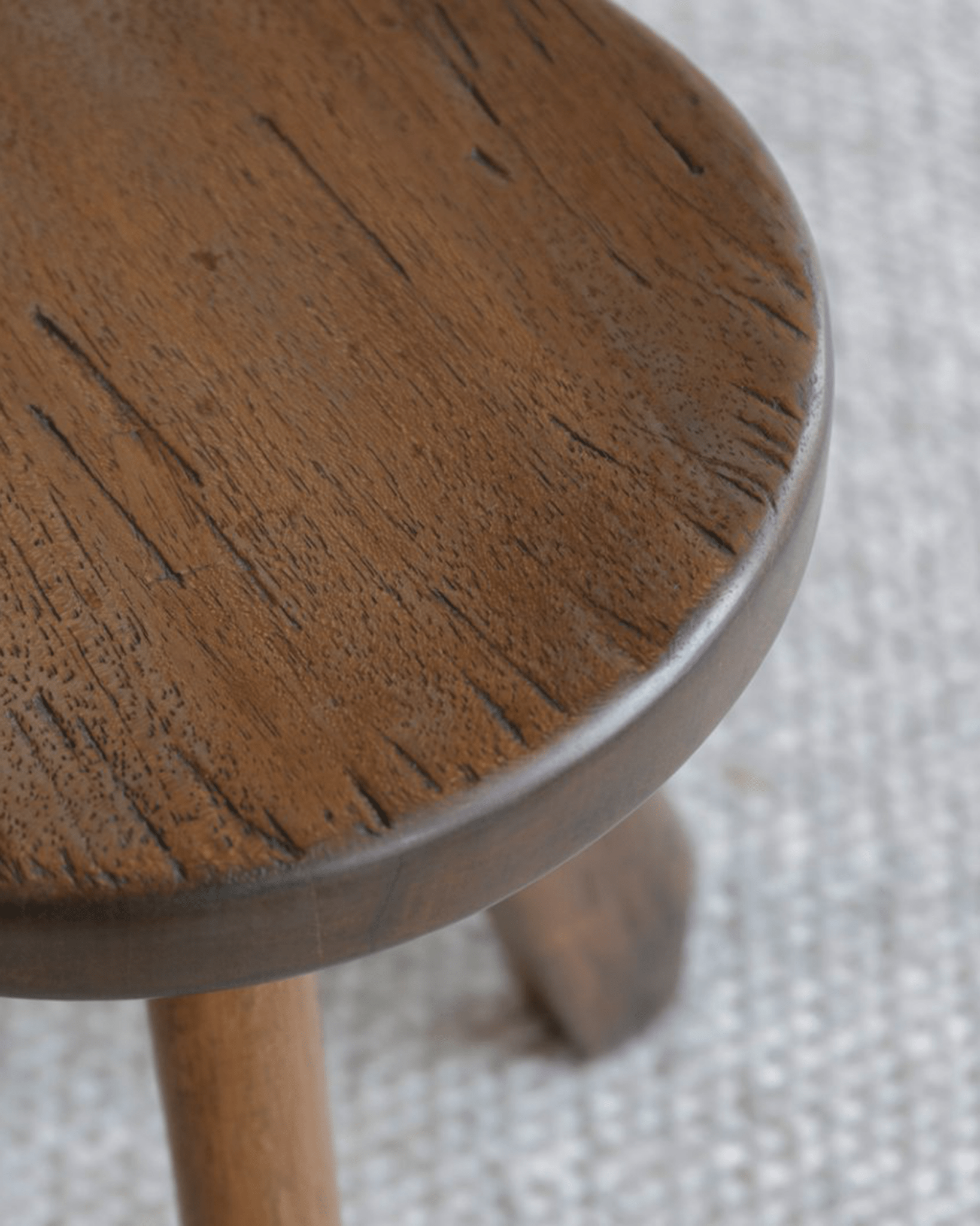 Natural wood French stool close-up, showcasing wood grain and round seat for versatile seating.