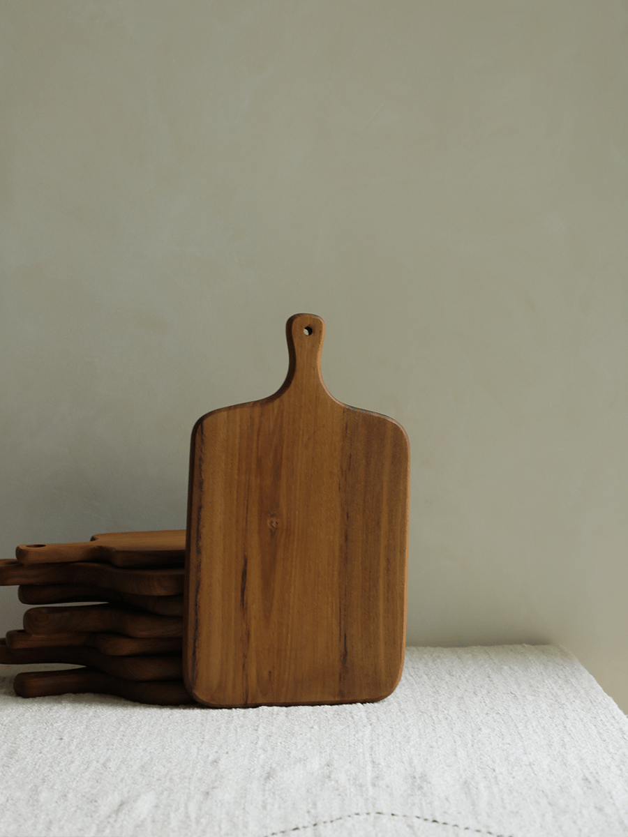 Wooden cutting boards with handles, stacked on white surface, natural wood grain. Product shot.