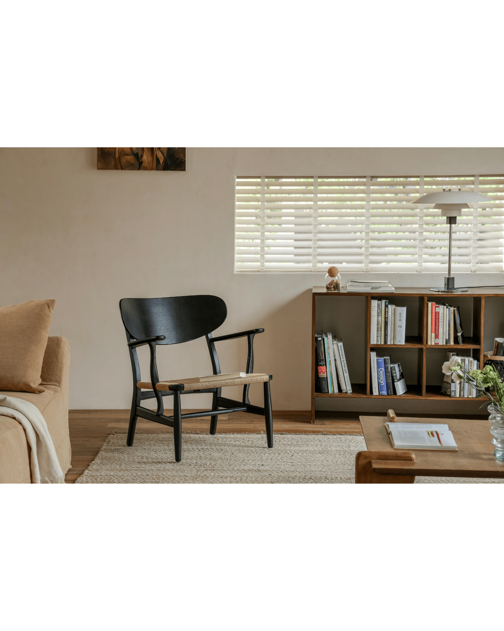 CH22 Lounge Chair in black frame with woven paper cord seat in modern living room, Scandinavian design.