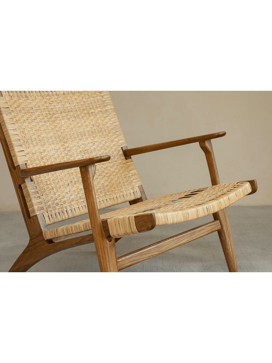 Horn Lounge Chair with oak frame and natural rattan seat, ergonomic design, handcrafted for comfort.