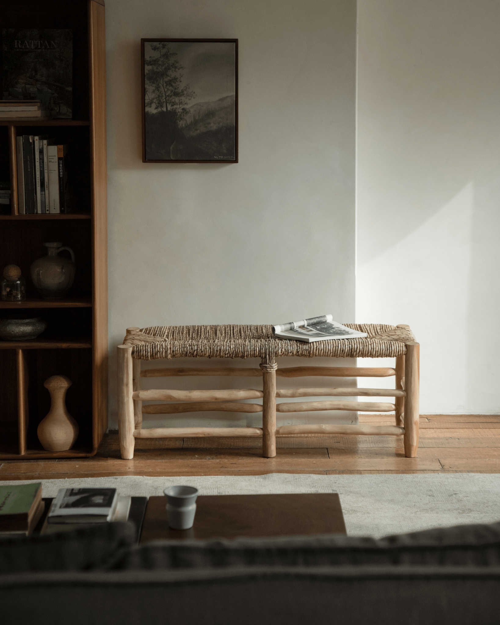 Isla Bench in natural setting with woven pandan leaf seat, solid teak frame, and magazine.