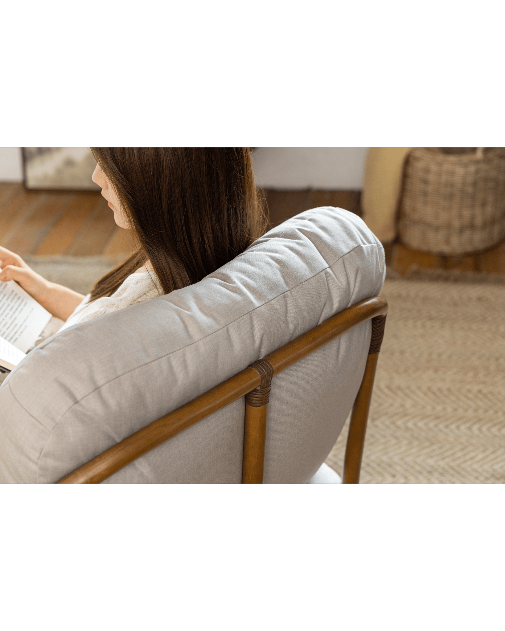 Woman relaxing on Tofu Lounge Sofa, reading book, light gray cushion and rattan frame, comfortable seating