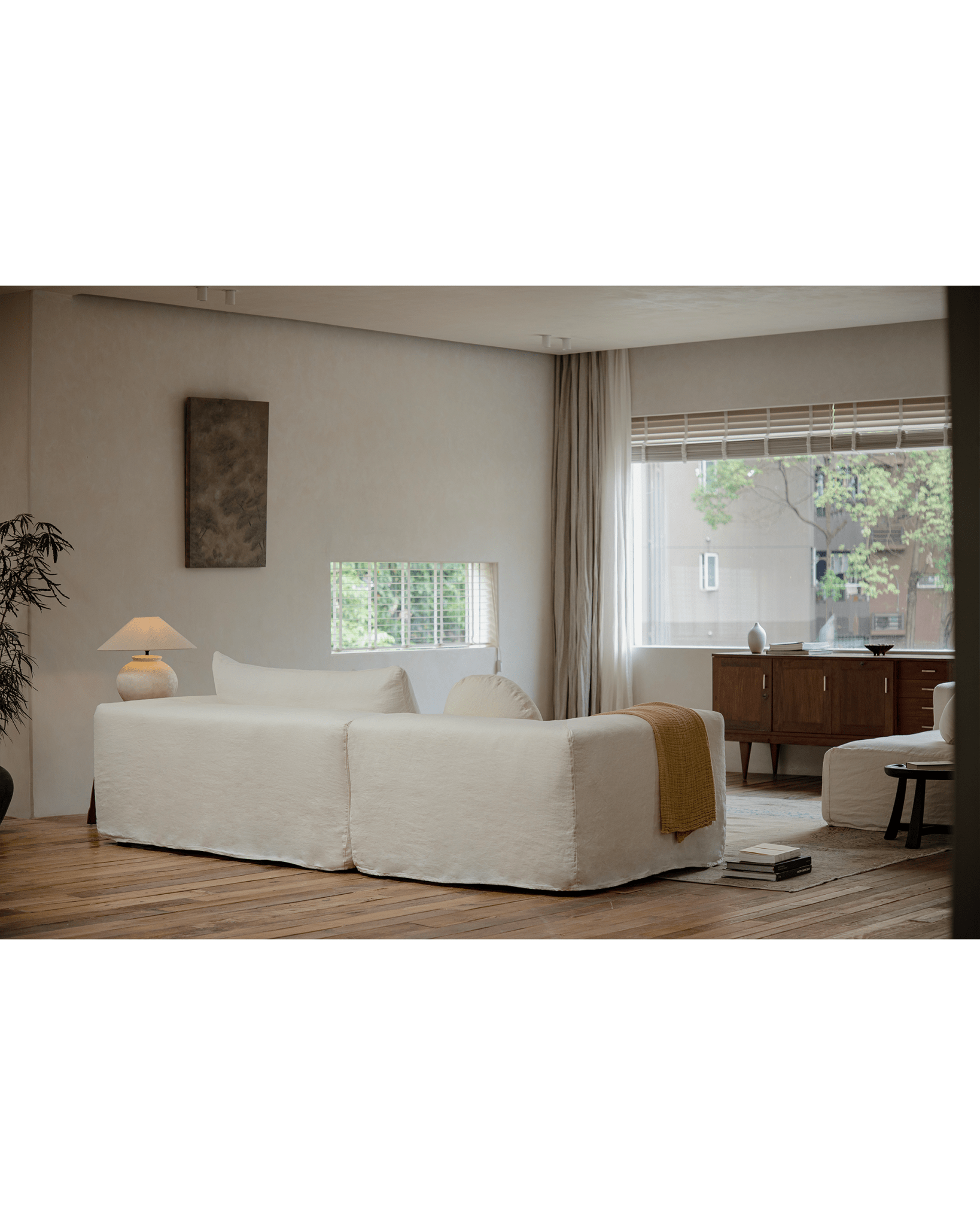 Doma Sectional Sofa in white linen, modular design with wide armrests in a bright, airy living space