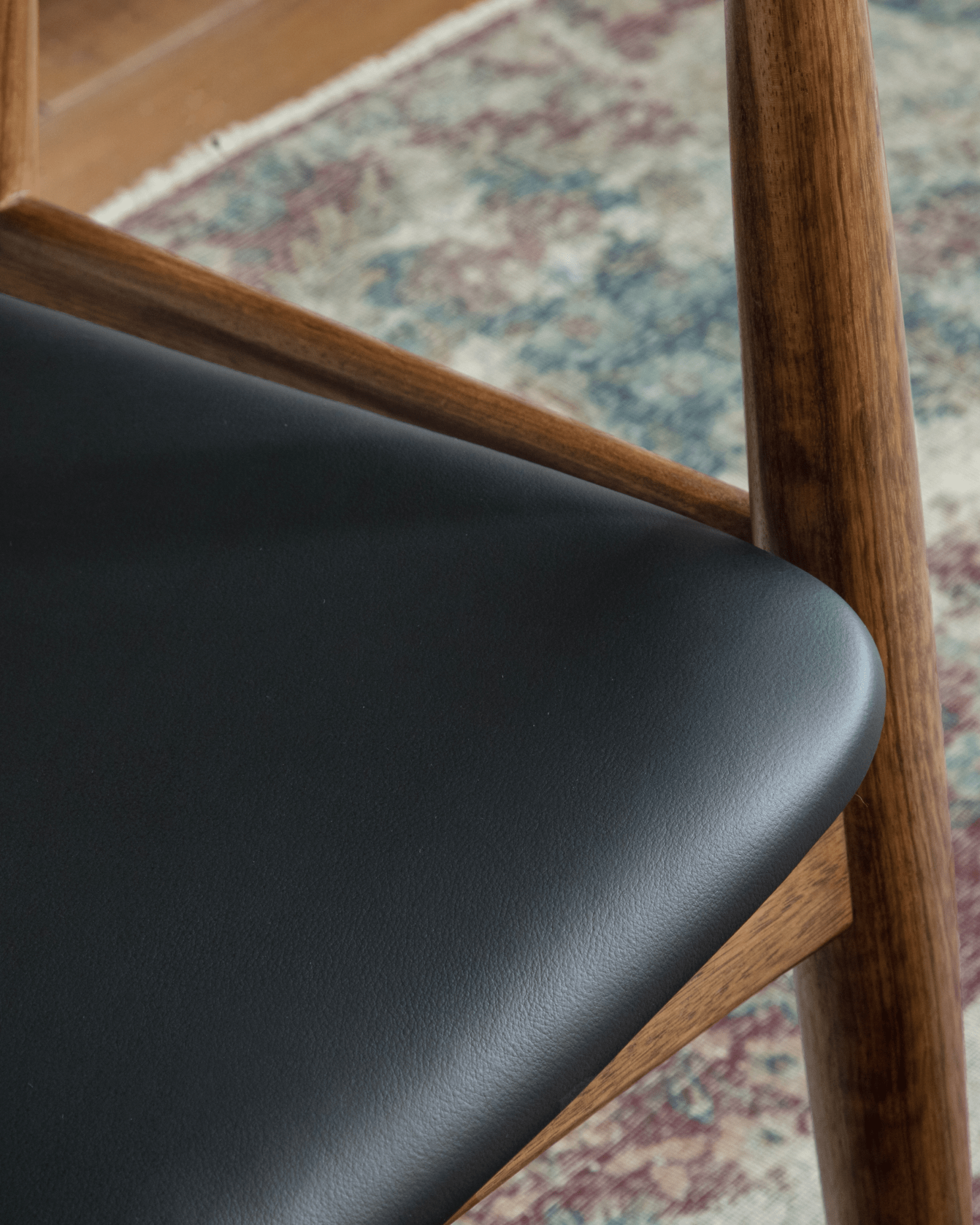 CH34 Yoke Chair detail: black leather seat with ebony wood frame, mid-century modern design.