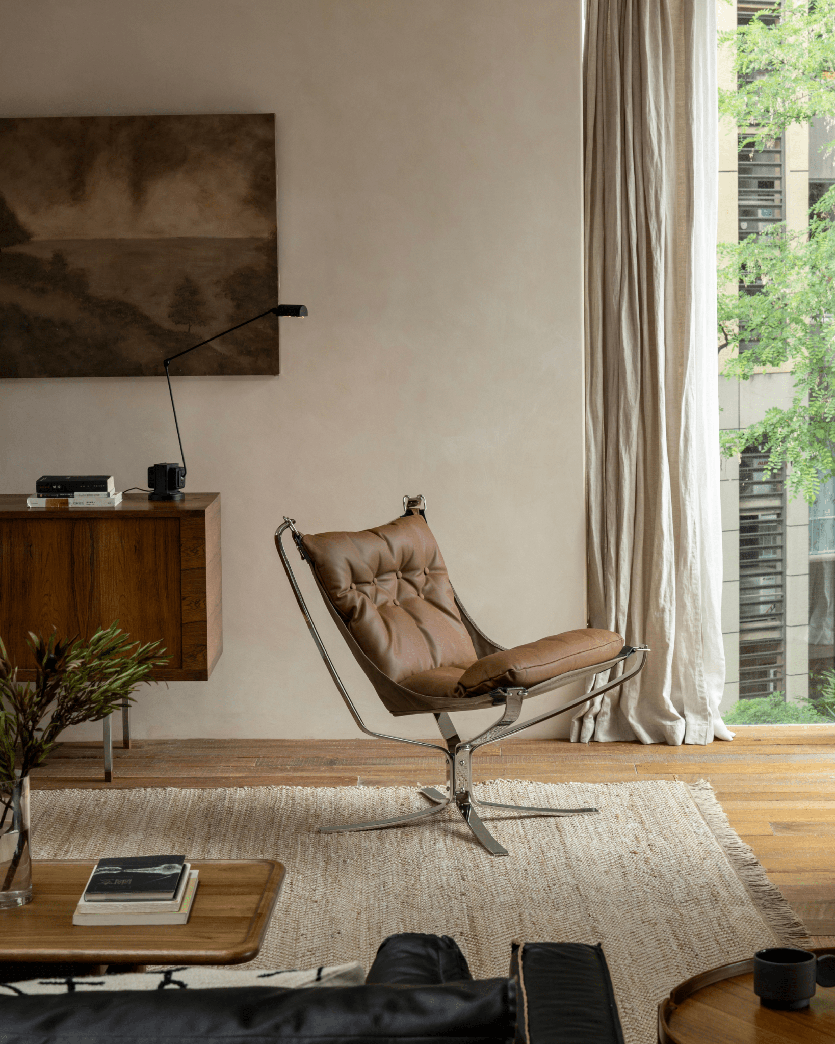 Brown leather Falcon Chair with stainless steel frame, Scandinavian design, in a modern living room setting