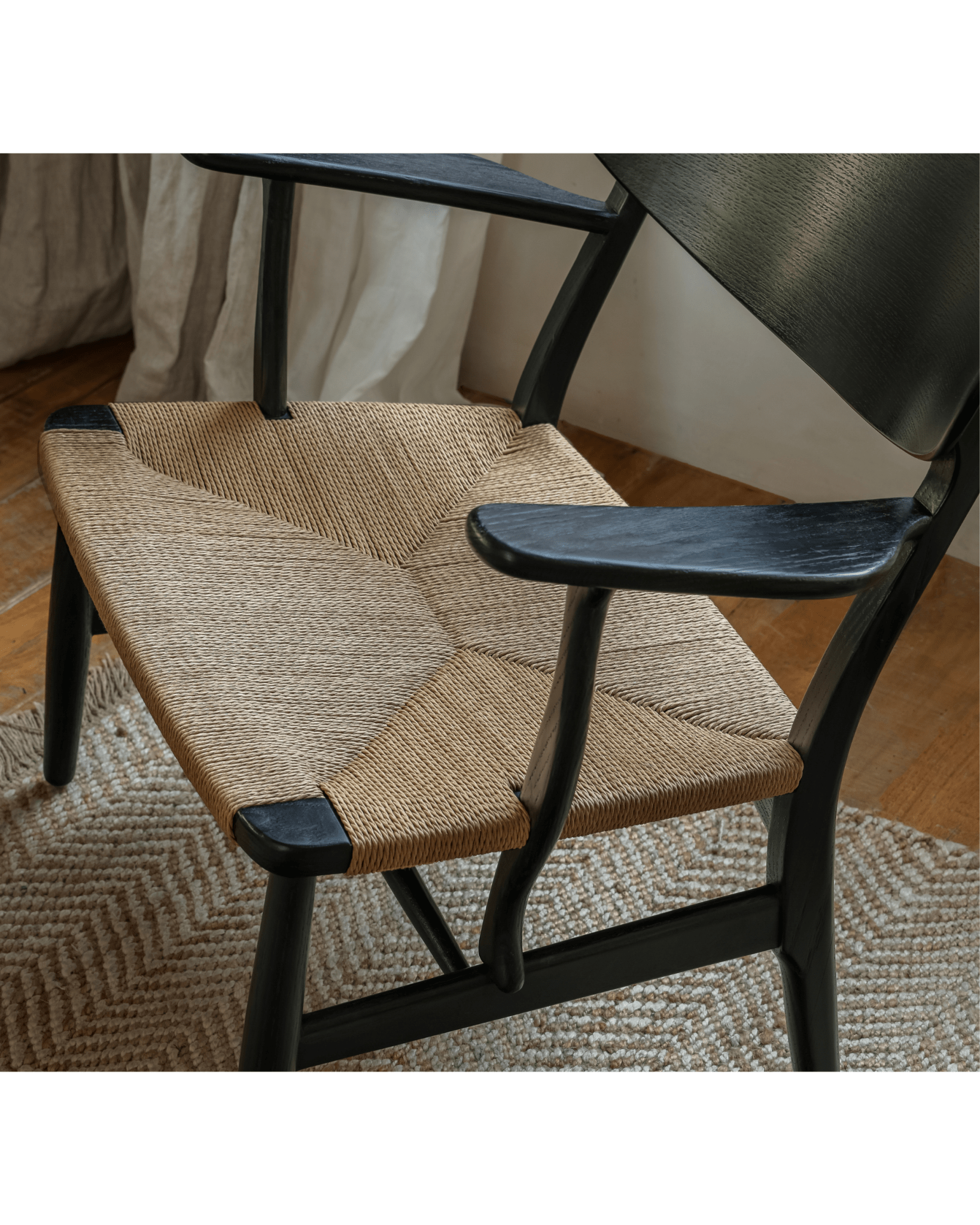 CH22 Lounge Chair with black frame and paper cord seat. Scandinavian design icon for modern interiors.