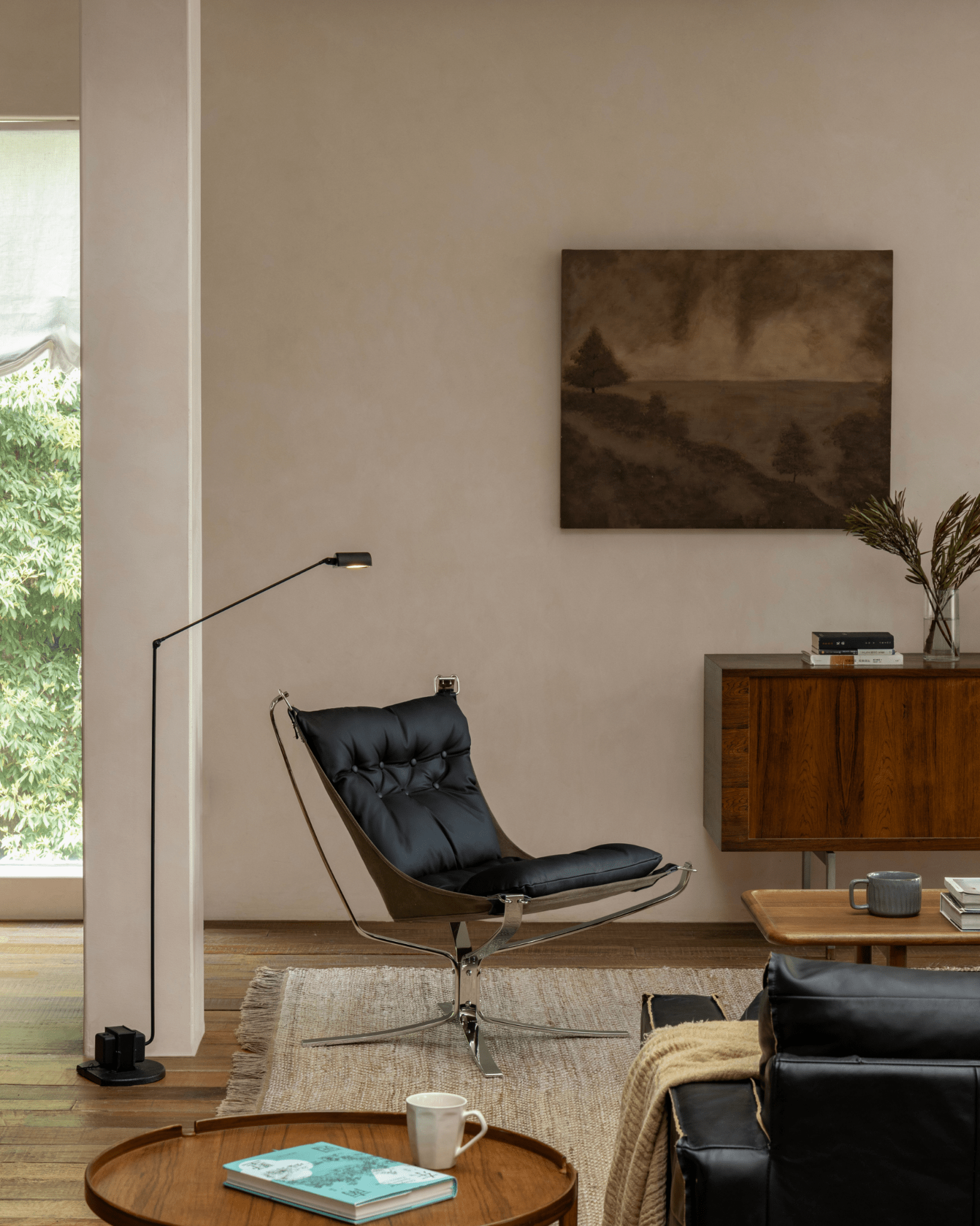 Black Falcon Chair in a modern living room setting, Scandinavian design, stainless steel frame, leather cushion