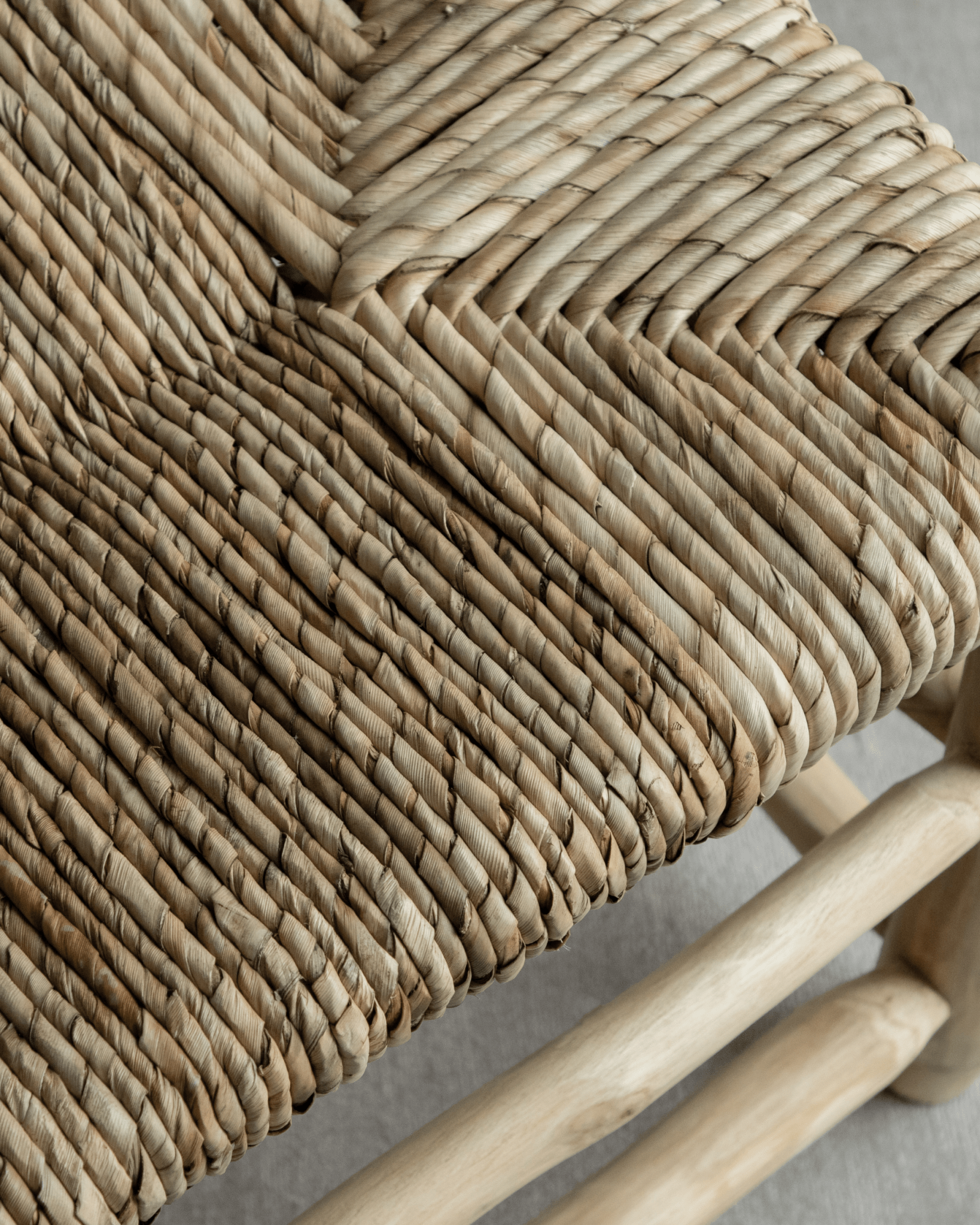 Close-up of woven pandan leaf seat detail and teak frame of the Isla Bench, modern organic design