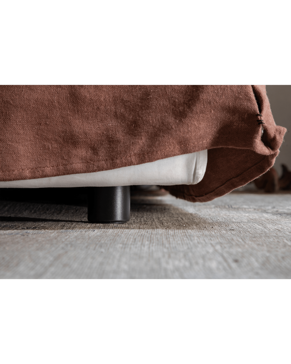 Freya Linen Bed detail: Terracotta linen upholstery, black leg, and wooden floor for peaceful sleep