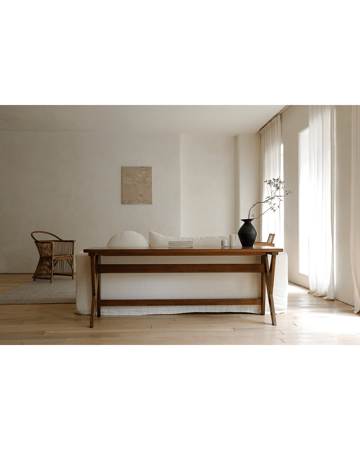 Teak writing desk in a modern living room, showcasing wood grain and design, with sofa and decorative elements.