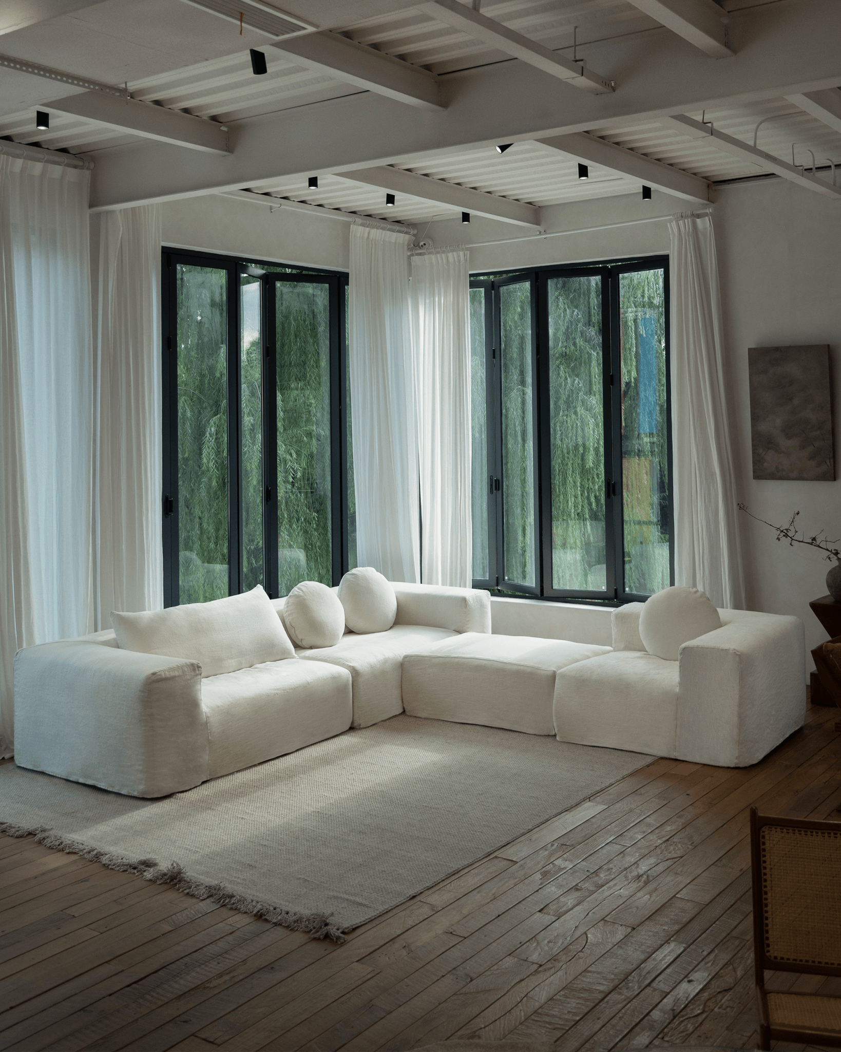 Doma Sectional Sofa with white linen, wide armrests, and modular design in a spacious, bright living room.
