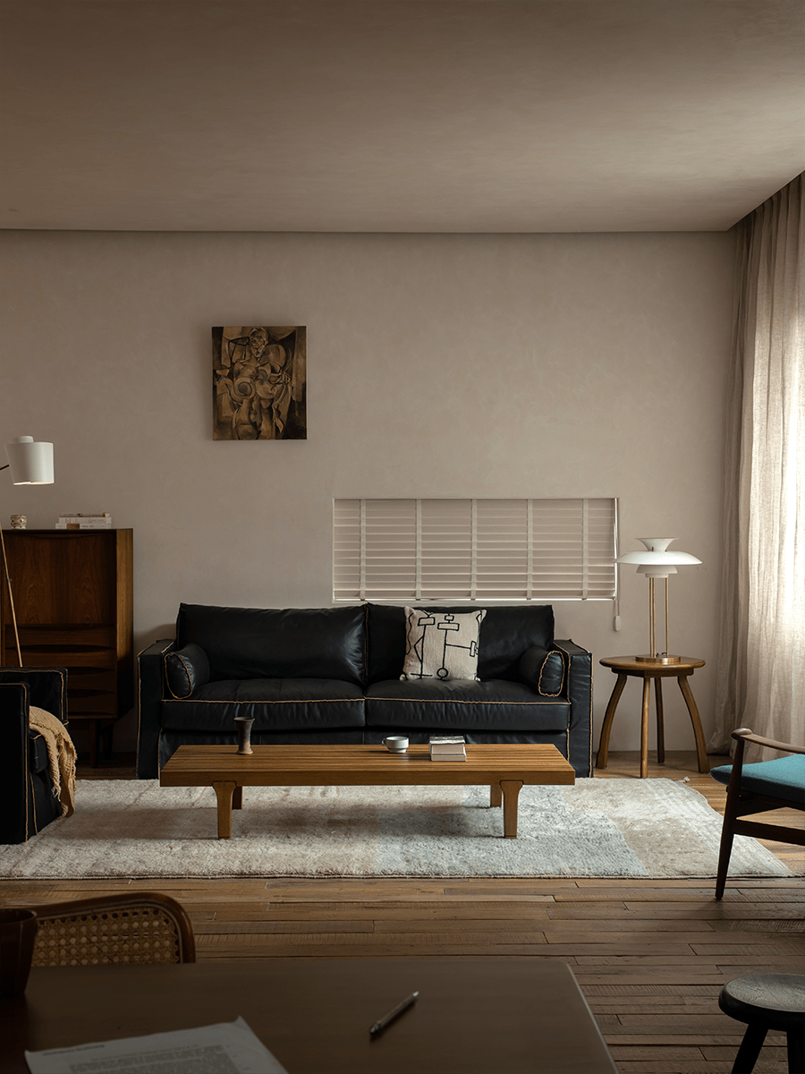 ZM Daybed Coffee Table in modern living room setting with a black leather sofa, wood flooring, and art.