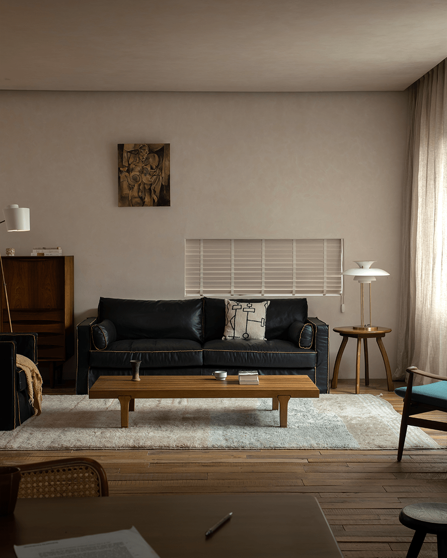 ZM Daybed Coffee Table in modern living room setting with a black leather sofa, wood flooring, and art.