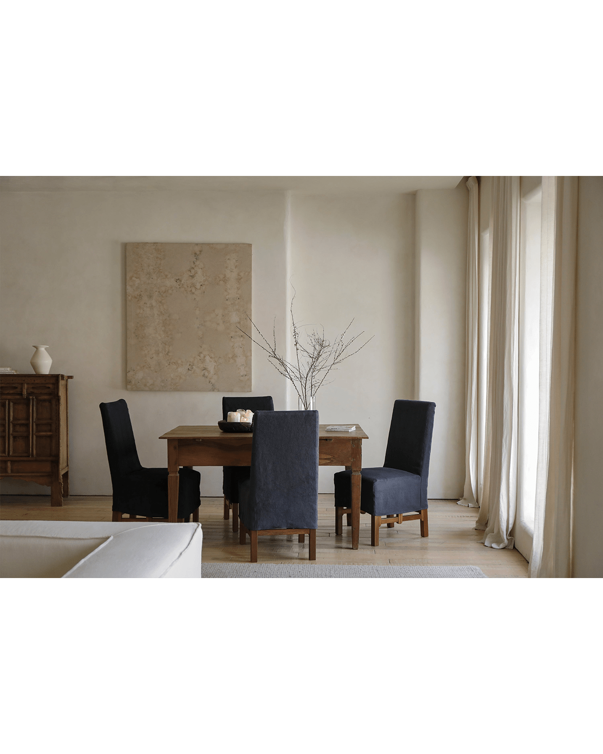 Feast Dining Chair in a modern dining room setting. Dark blue linen slipcover, wood frame, perfect for modern home decor.
