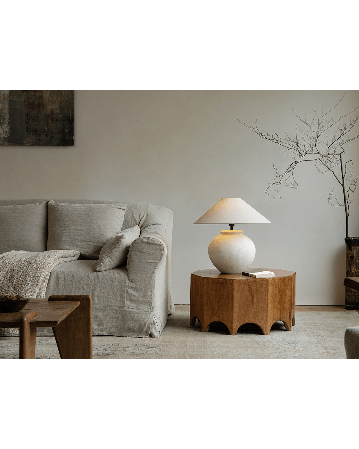 Decagon Side Table in a modern living room, showcasing solid rainwood craftsmanship, geometric design and a stylish lamp