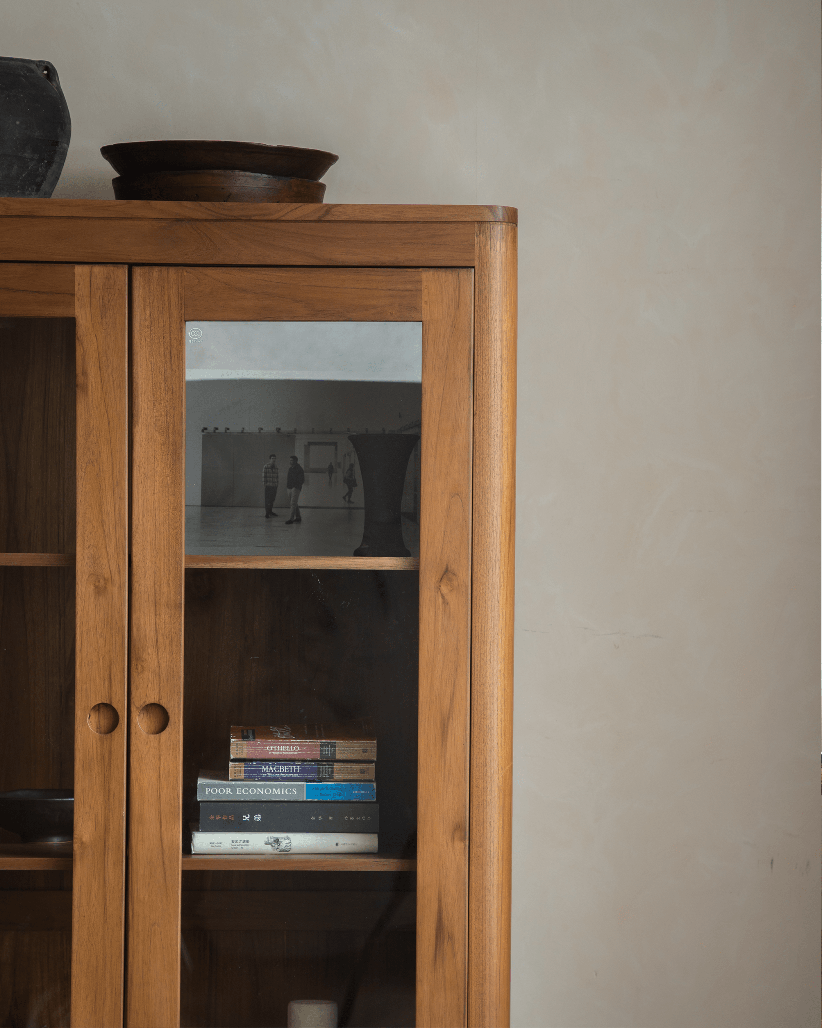 Reve Teak Bookcase with double glass doors. Display shelf with books and warm teak wood grain.