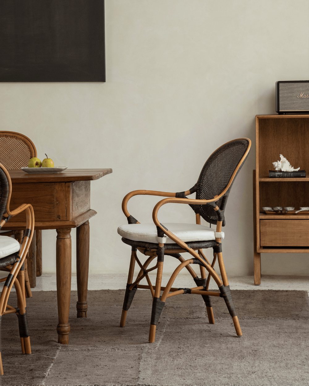 Areca Rattan Chair with black handwoven backrest, natural rattan frame and white cushion, with Marshall speaker