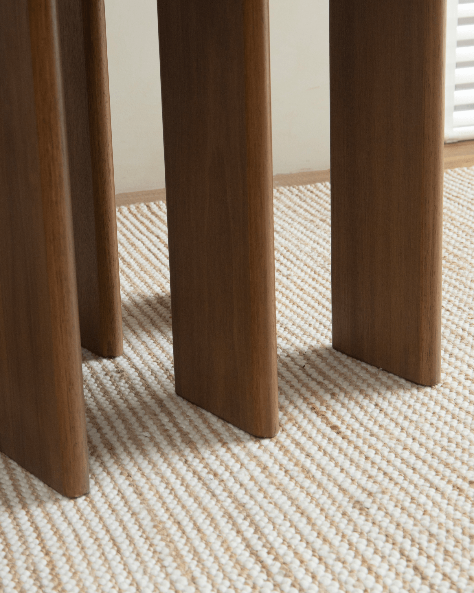 Titan Teak Table detail: Teak wood legs with multi-leg design, on a neutral rug, showcasing the quality and style