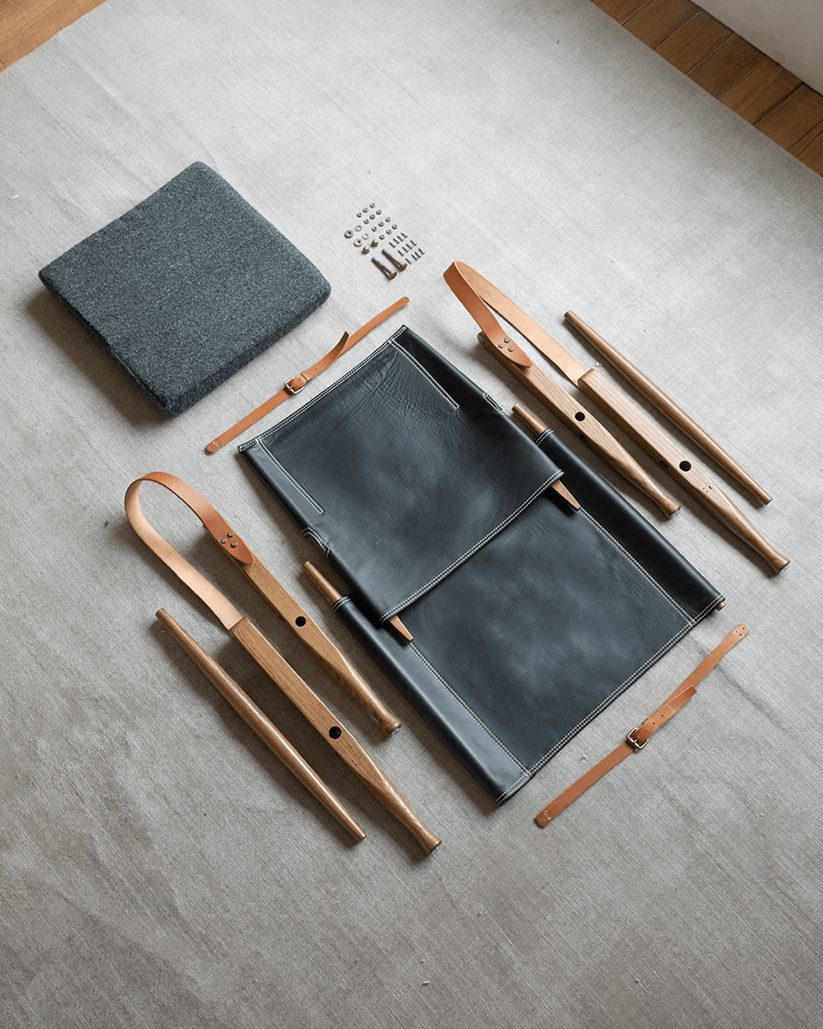 Safari Chair disassembled: US Red Oak frame, black leather seat and backrest, leather straps, cushion, and hardware.